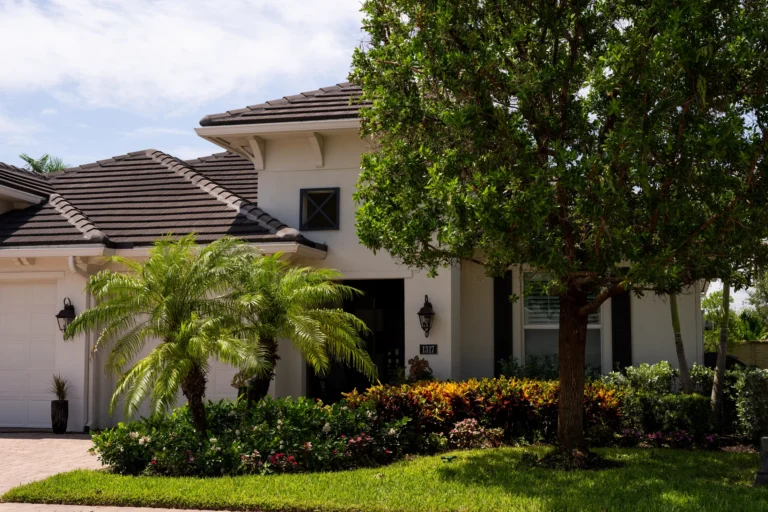 Home with a shade tree, palms and a manicured front lawn
